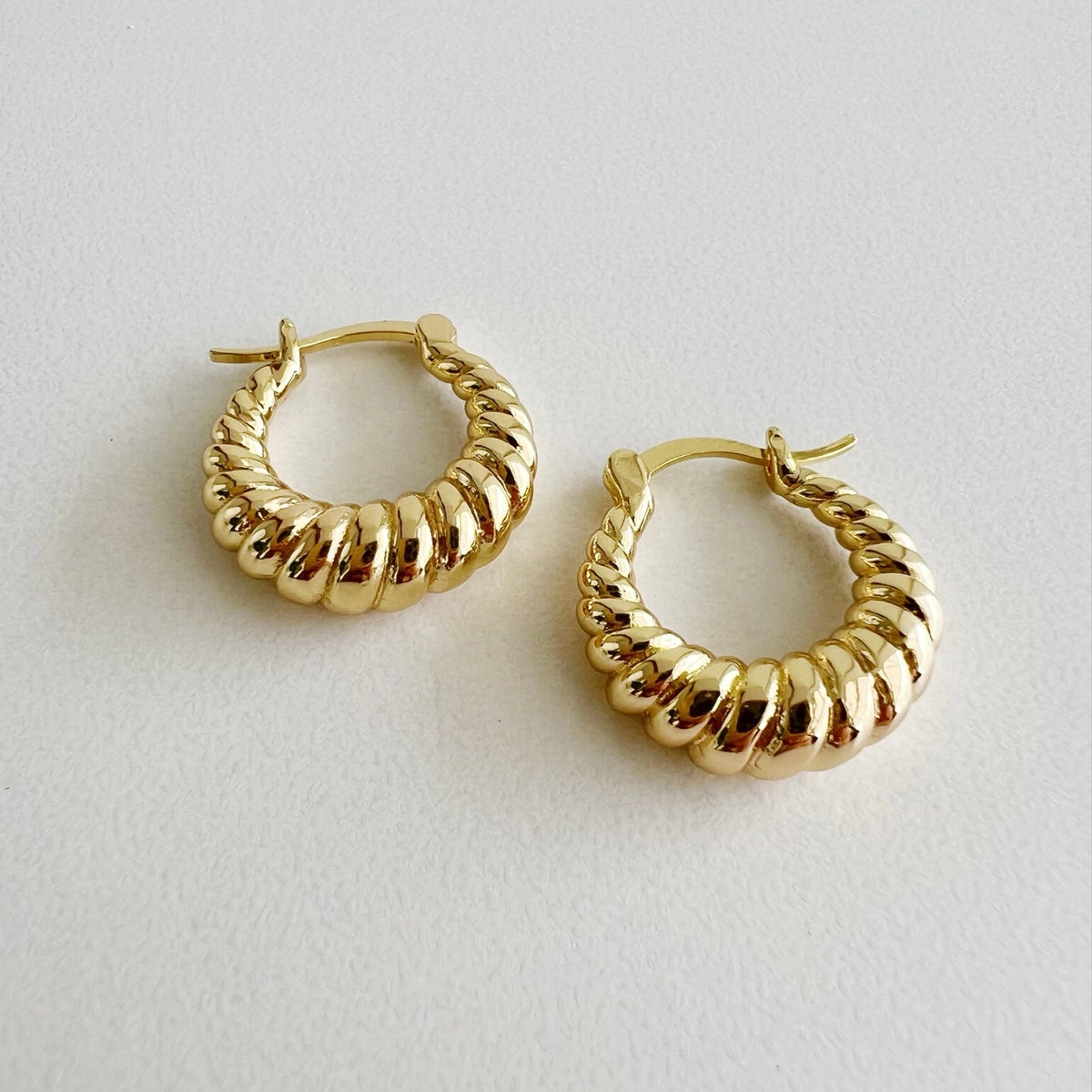 Close-up of twisted 14K gold-filled hoop earrings with hinge backing