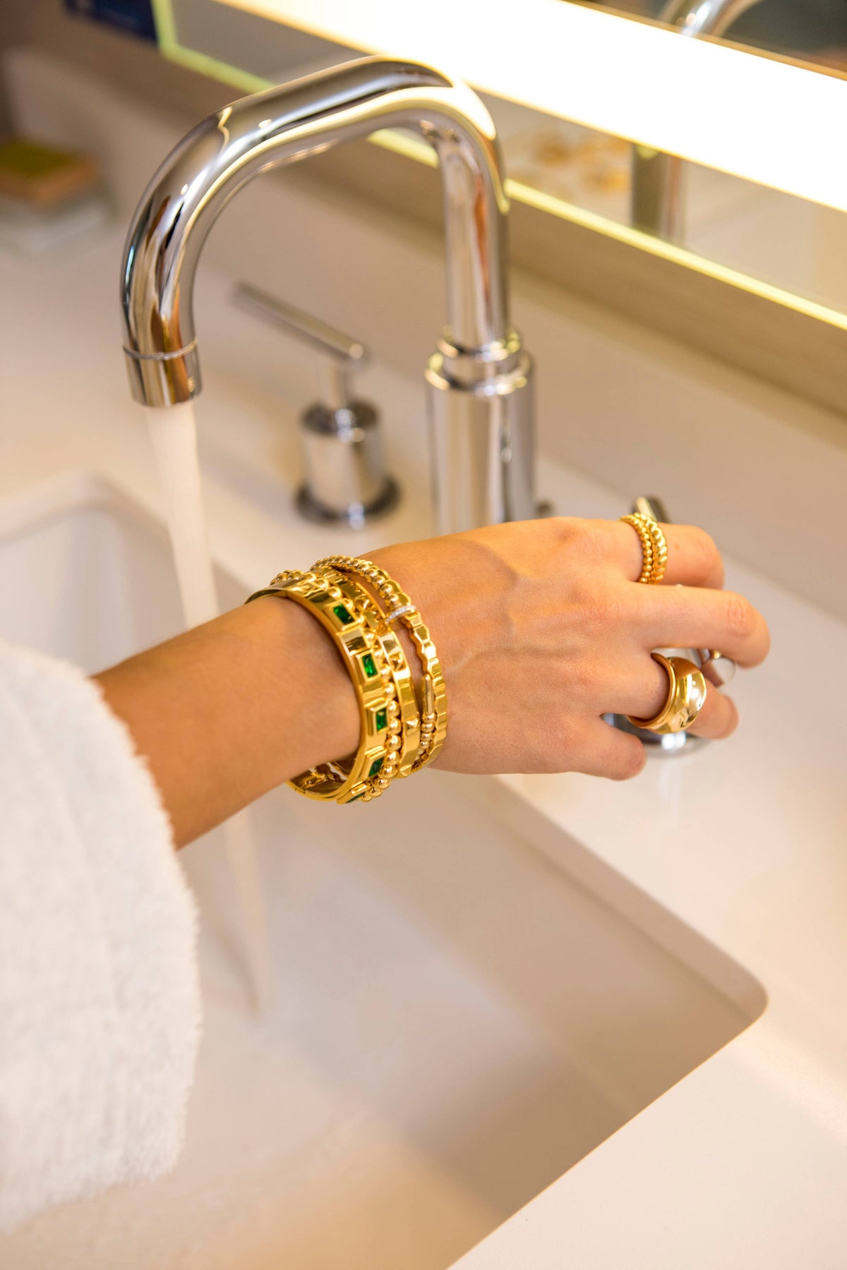 Emerald bracelet styled with layered gold jewelry