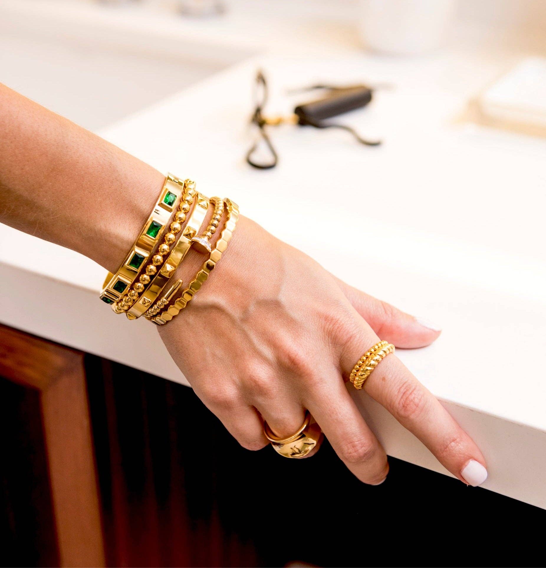 Close-up of emerald gemstones on gold bangle bracelet