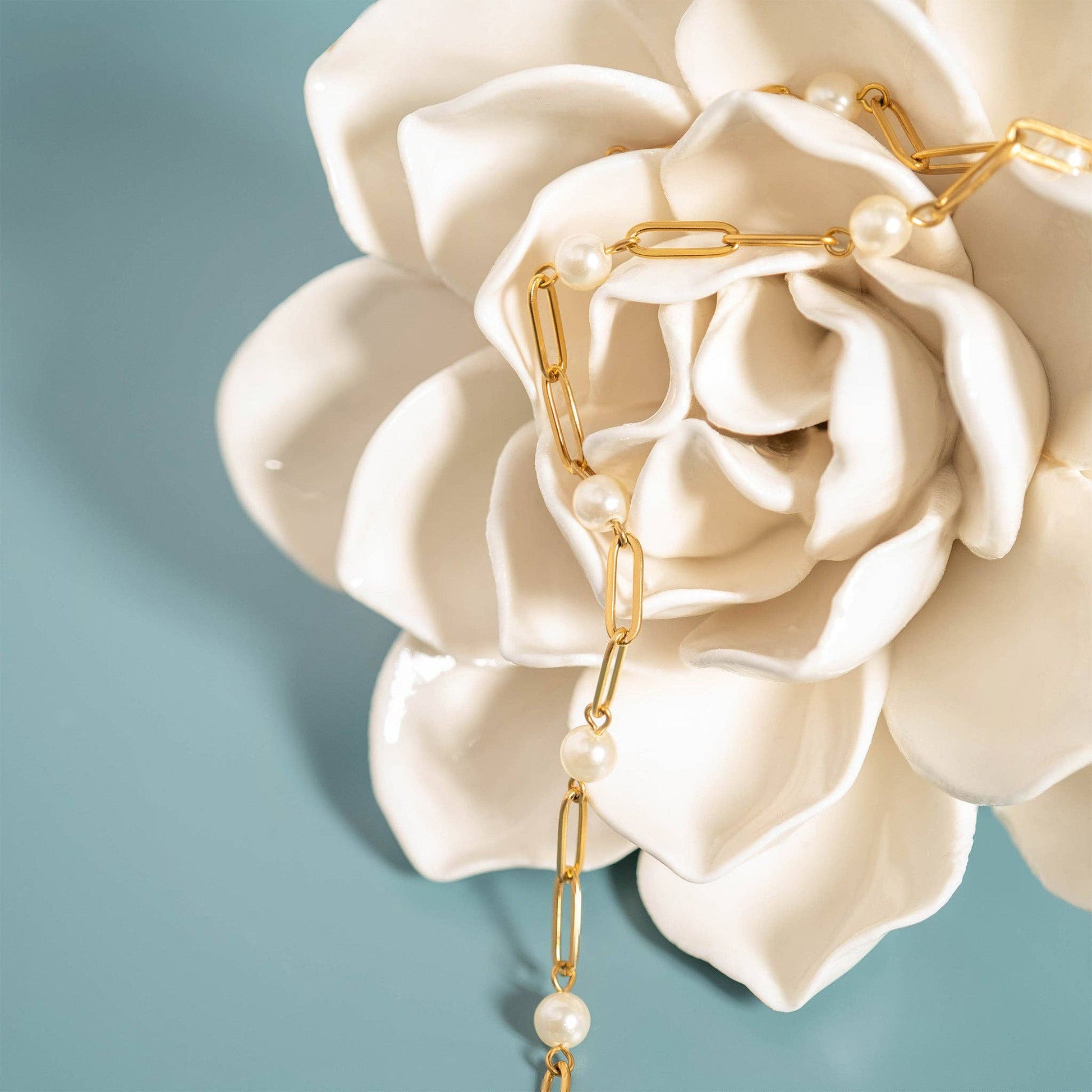 Close-up of luminous pearl accents on a gold paperclip bracelet