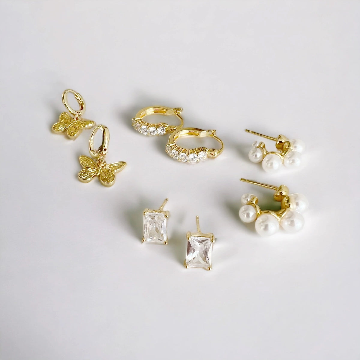 Pearl hoop earrings laying next to other earring to show sizing with everyday gold jewelry 