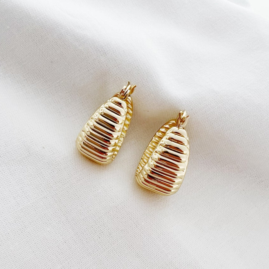 Close-up of textured dome design on gold hoop earrings