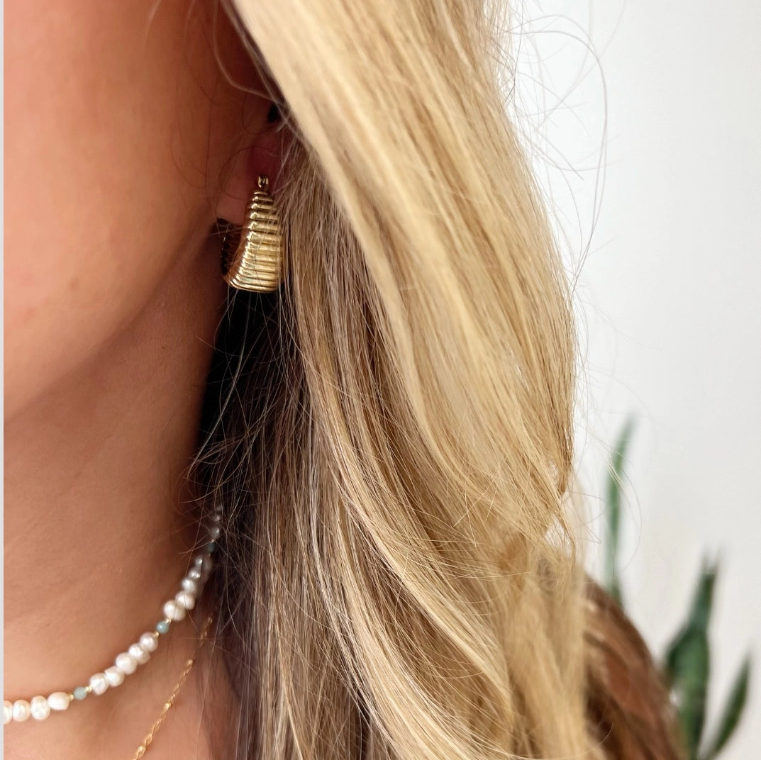 Woman wearing textured gold hoop earrings styled for everyday jewelry